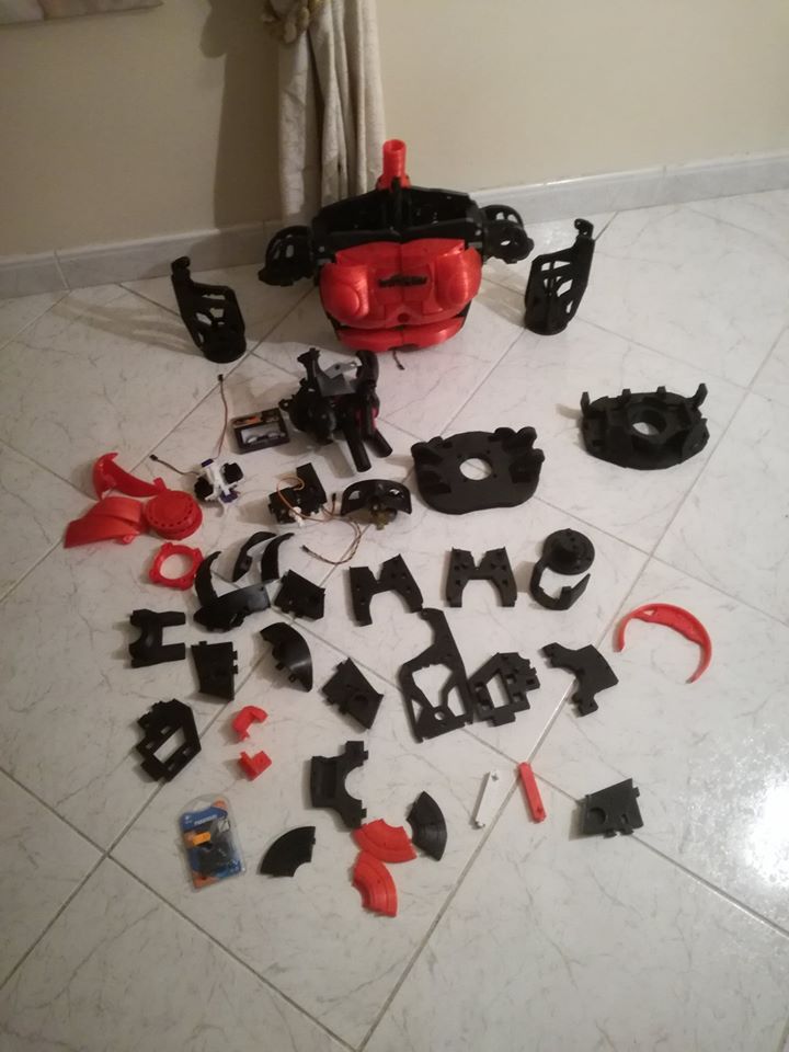 Dozens of freshly 3D-printed black and red robot parts laid out on a tiled floor, ready for assembly.